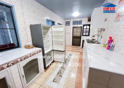 Spacious kitchen with tiled walls and floors, featuring a refrigerator, sink, and ample countertop space