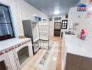 Spacious kitchen with tiled walls and floors, featuring a refrigerator, sink, and ample countertop space