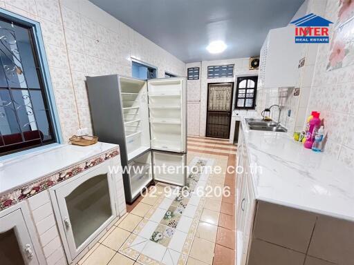 Spacious kitchen with tiled walls and floors, featuring a refrigerator, sink, and ample countertop space