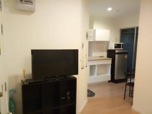 Living area with TV, shelves, and kitchen view