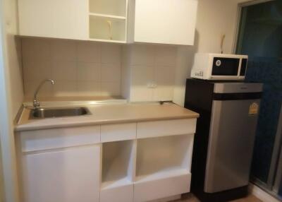 Kitchen with stainless steel sink, countertop, microwave, and refrigerator