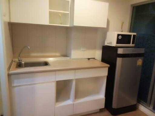 Kitchen with stainless steel sink, countertop, microwave, and refrigerator