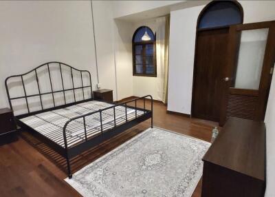 Spacious bedroom with iron bed frame, wooden floors, and arched windows