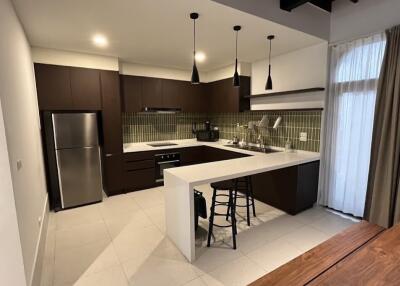 Modern kitchen with dark wood cabinets, stainless steel appliances, and a breakfast bar