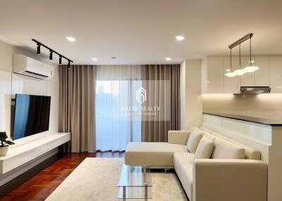 Modern living room with a white sofa, glass coffee table, wall-mounted TV, and air conditioning