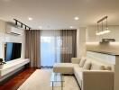 Modern living room with a white sofa, glass coffee table, wall-mounted TV, and air conditioning