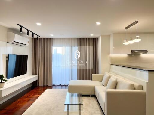 Modern living room with a white sofa, glass coffee table, wall-mounted TV, and air conditioning