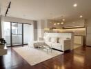 Spacious living room with a white sofa, glass coffee table, and open kitchen in the background