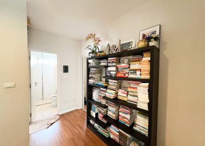 A hallway with a bookshelf filled with books leading to a bathroom