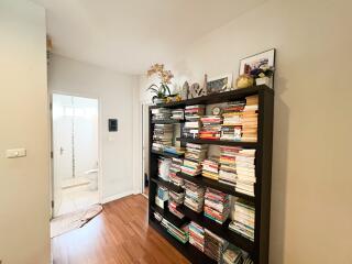 A hallway with a bookshelf filled with books leading to a bathroom