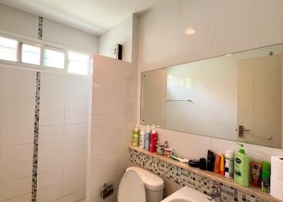 Modern bathroom with white tiles, toilet, sink, and walk-in shower