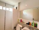 Modern bathroom with white tiles, toilet, sink, and walk-in shower