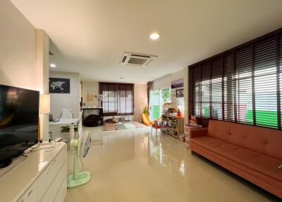 Spacious living room with modern decor, featuring a TV, sofa, air conditioning, and large windows.