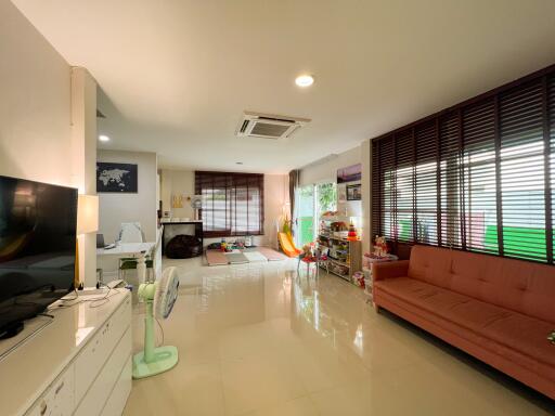 Spacious living room with modern decor, featuring a TV, sofa, air conditioning, and large windows.