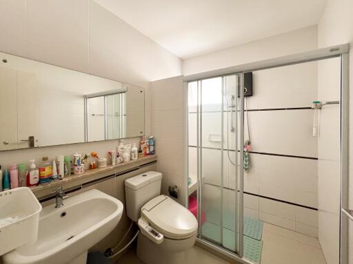 A modern bathroom with a sink, toilet, mirrored cabinet, and glass-enclosed shower.