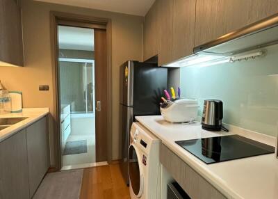 Modern kitchen with wooden flooring, black refrigerator, white countertops, and built-in appliances