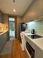 Modern kitchen with wooden flooring, black refrigerator, white countertops, and built-in appliances