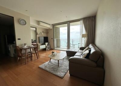 Modern living room with comfortable leather sofa, coffee table, and dining area with a view of the balcony.