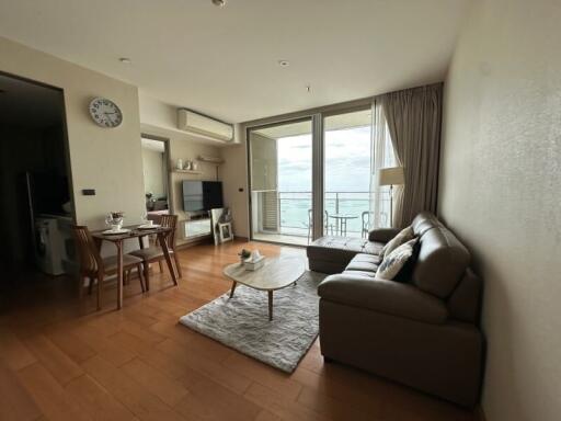 Modern living room with comfortable leather sofa, coffee table, and dining area with a view of the balcony.