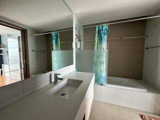 Modern bathroom with large mirror, bathtub, and sink