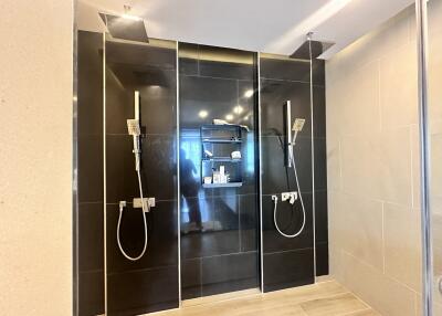Modern bathroom with dual rain showers and black tile wall