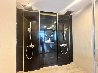 Modern bathroom with dual rain showers and black tile wall