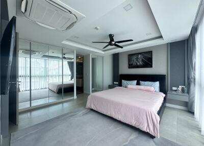 Spacious modern bedroom with a large bed, mirrored wardrobe, and ceiling fan