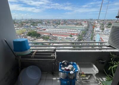 View of a city from a balcony with various household items and potted plants