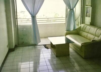 Living room with a sofa and a coffee table, adjacent to a balcony with curtains