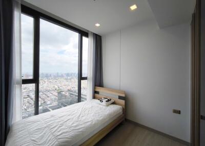 A small bedroom with a large window offering a city view