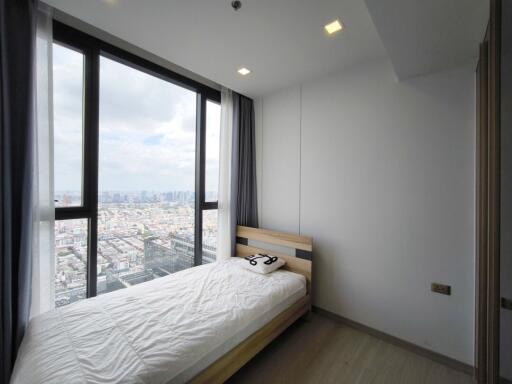 A small bedroom with a large window offering a city view