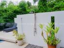 Outdoor shower next to a pool surrounded by lush greenery