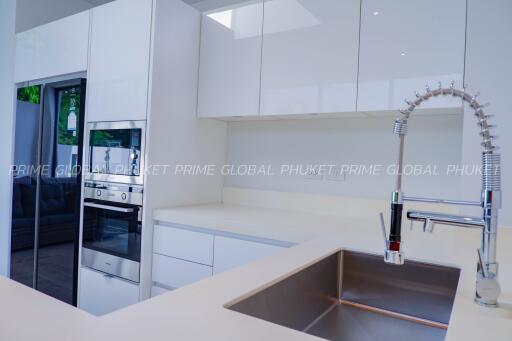 Modern white kitchen with stainless steel appliances and a sleek faucet