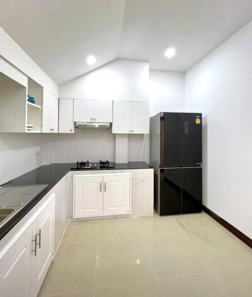 Modern kitchen with white cabinets, black countertops, and stainless steel appliances