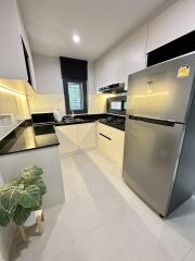 Modern kitchen with stainless steel appliances, black countertops, and white cabinets