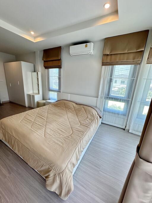 Well-lit bedroom with a large bed, air conditioning, and ample natural light.