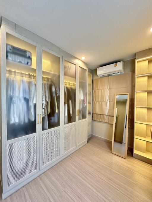 Spacious walk-in wardrobe with wooden flooring and modern lighting