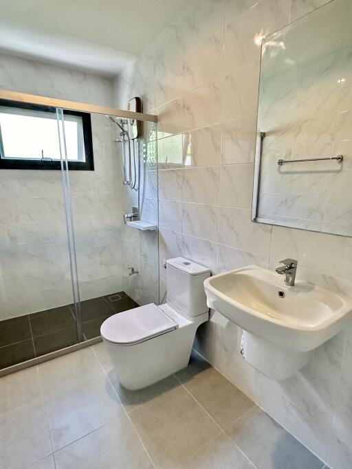 Modern bathroom with glass shower, toilet, and sink