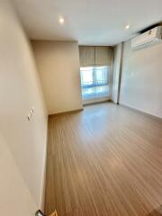 Empty bedroom with wooden flooring, air conditioning unit, and window with blinds