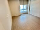 Empty bedroom with wooden flooring, air conditioning unit, and window with blinds