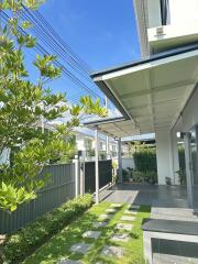 Exterior view of a modern house with a garden path and covered patio area.