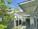 Exterior view of a modern house with a garden path and covered patio area.