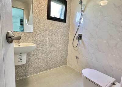 Modern bathroom with wall-mounted toilet, sink, and shower