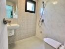 Modern bathroom with wall-mounted toilet, sink, and shower