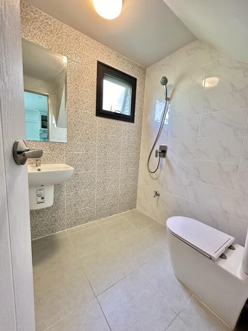 Modern bathroom with wall-mounted toilet, sink, and shower