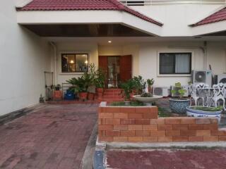 Front entrance of a residential building with plants and outdoor furniture