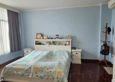 Spacious bedroom with wooden floor and blue walls