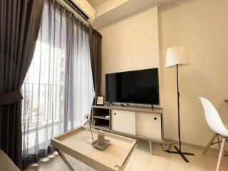 Modern living room with TV, coffee table, floor lamp, and large window with curtains