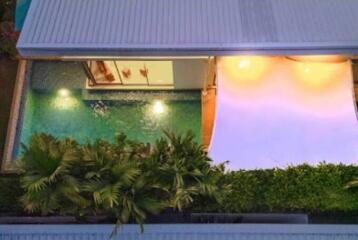 Aerial view of a modern home with a swimming pool and surrounding greenery