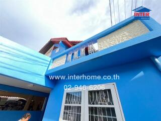 Brightly colored blue exterior of a building with visible windows and balcony